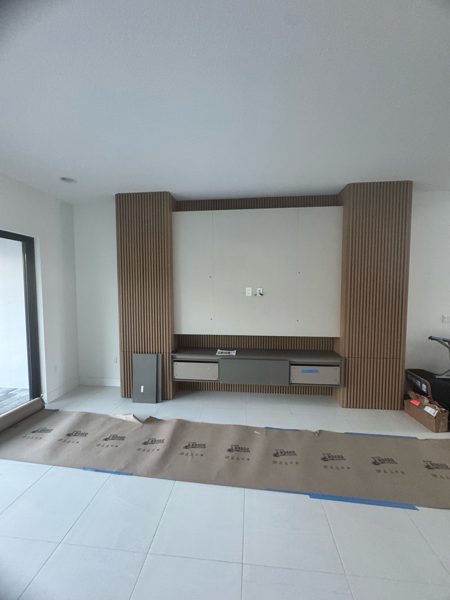 TV wall installation in progress with protective floor covering